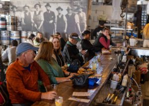 A crowded tap room in brickyard hollow, with patrons enjoying seasonal beers